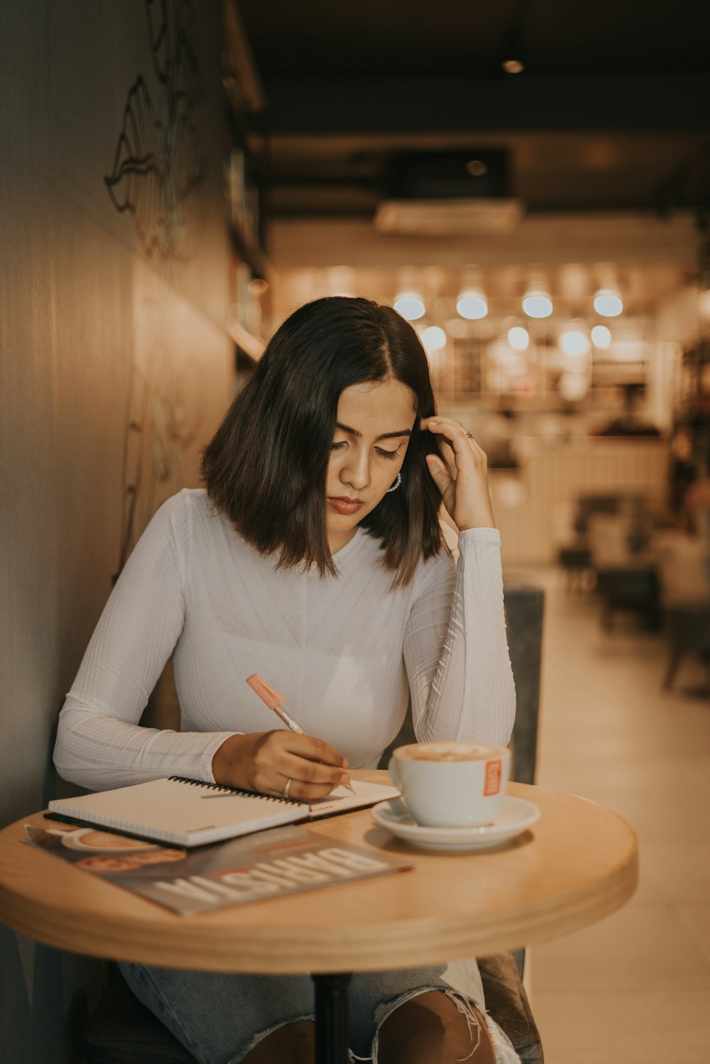 a woman sitting at a table writing in a notebook