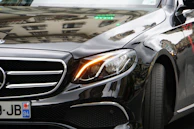 Close-up of a polished black Avanza with reflections of city lights on its surface.