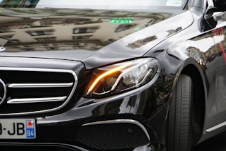 Close-up of a sleek black car with a mirror-like polished finish reflecting city lights.