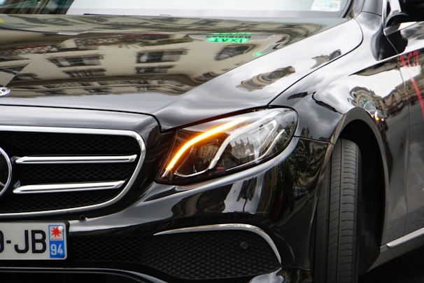 Close-up of a sleek black metal license plate frame with rose gold accents reflecting city lights.