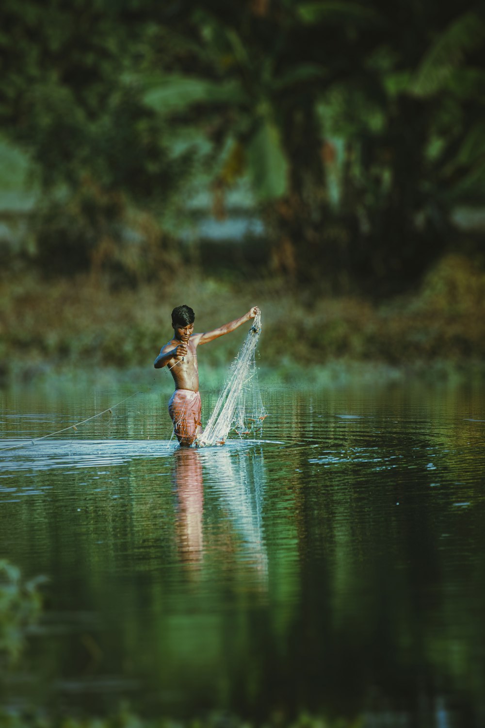 a boy in a body of water throwing a frisbee