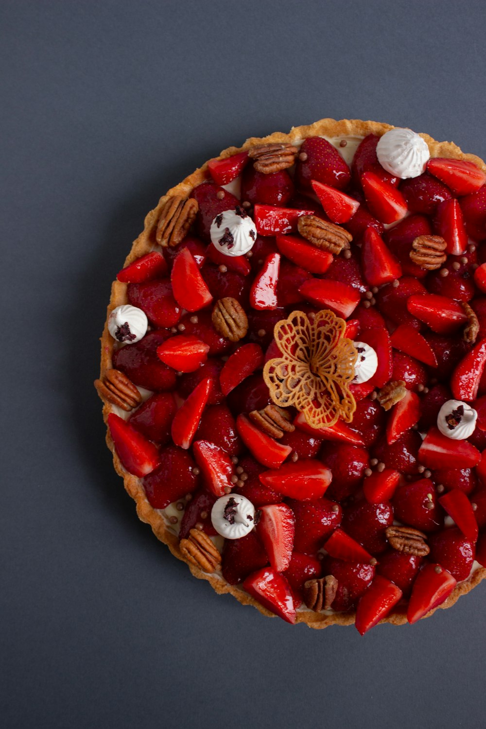 a pie topped with strawberries and nuts on top of a table