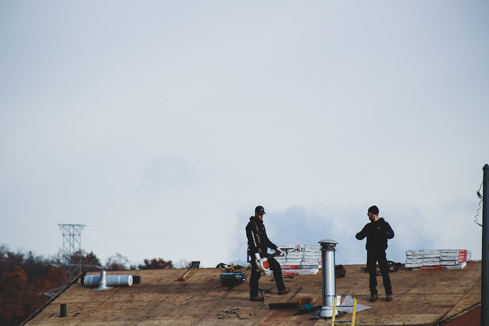 a couple of men standing on top of a roof