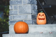 two carved pumpkins sitting on the steps of a house