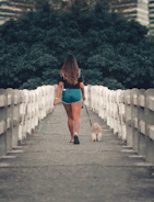 a woman walking a dog down a bridge