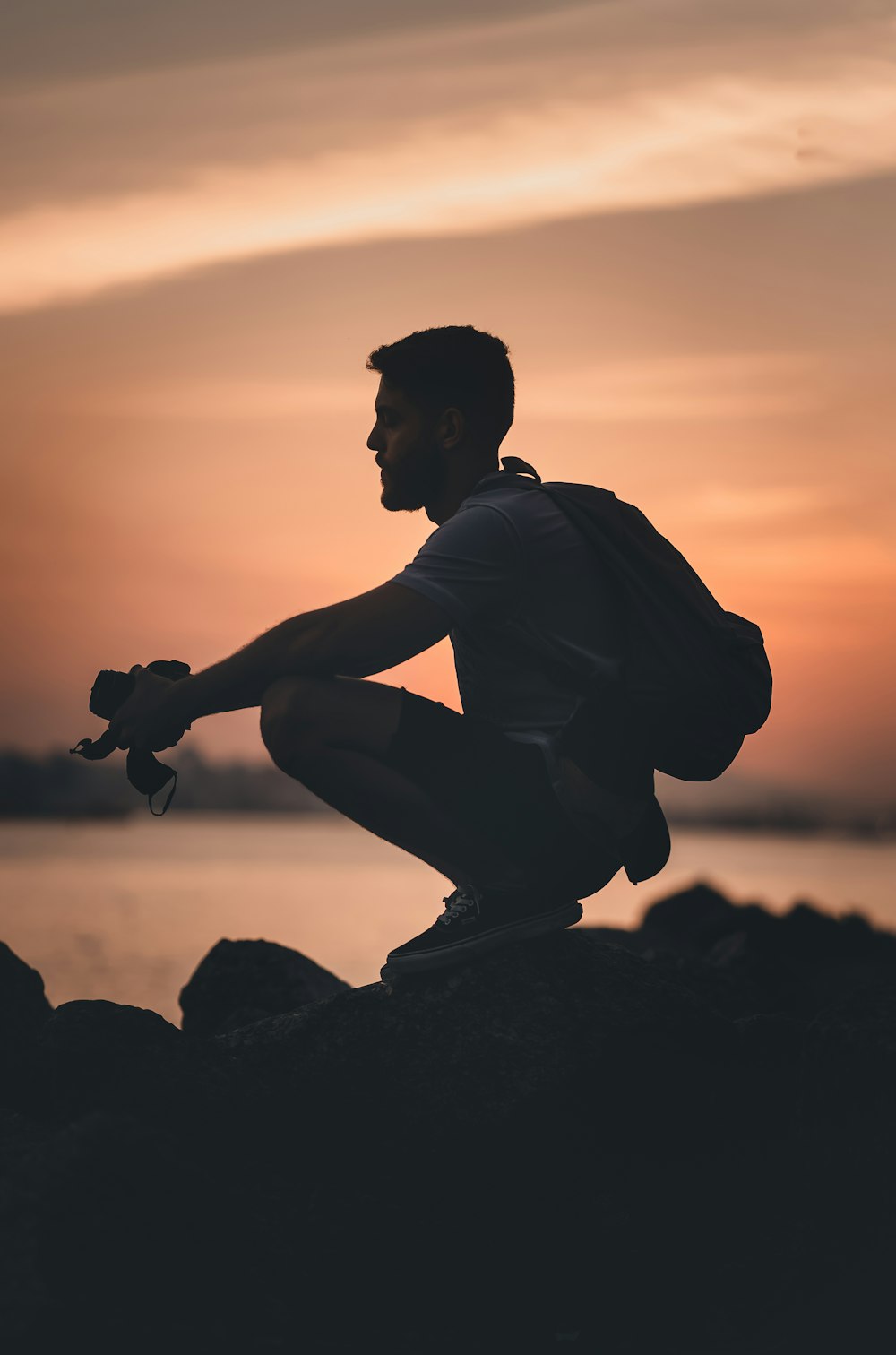 a man sitting on top of a rock next to a body of water