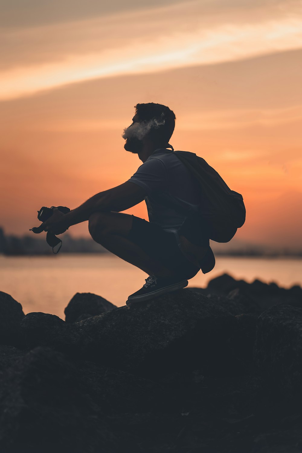 a man sitting on top of a rock next to a body of water