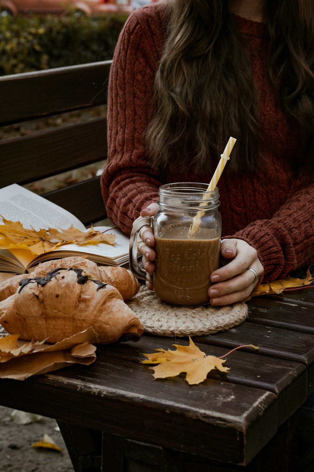 a woman sitting on a bench holding a cup of coffee