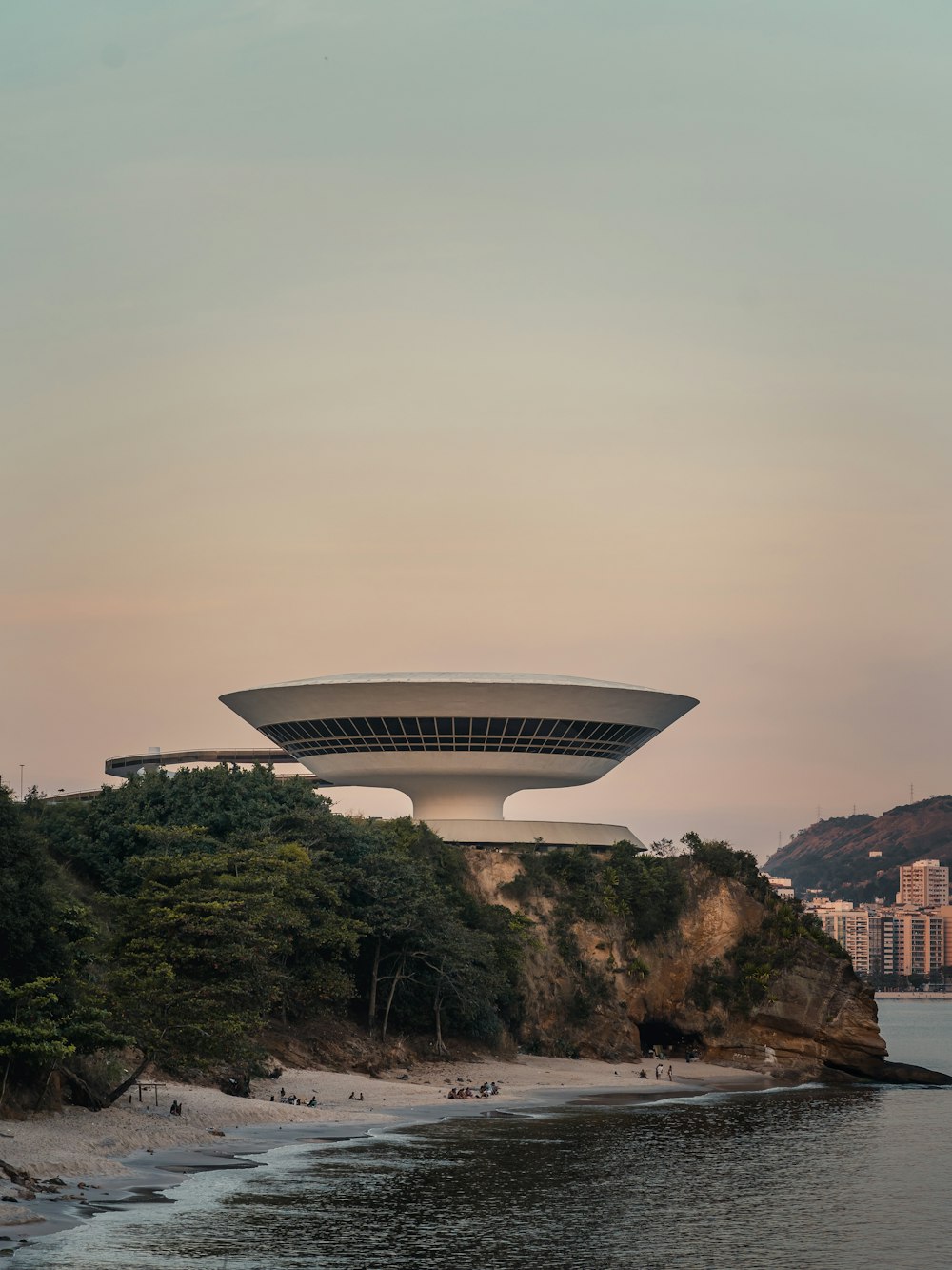 a large building on top of a hill next to a body of water