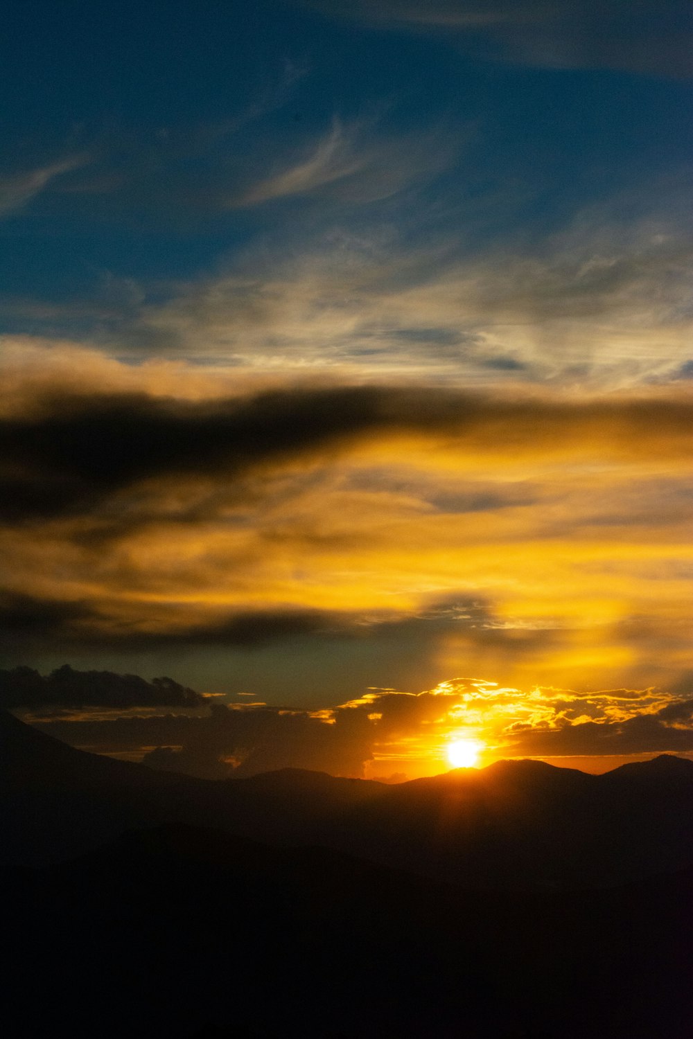 the sun is setting over a mountain range