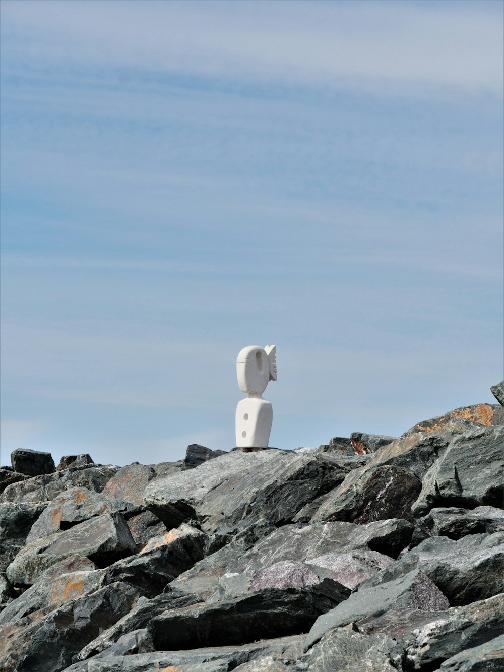 a white sculpture sitting on top of a pile of rocks