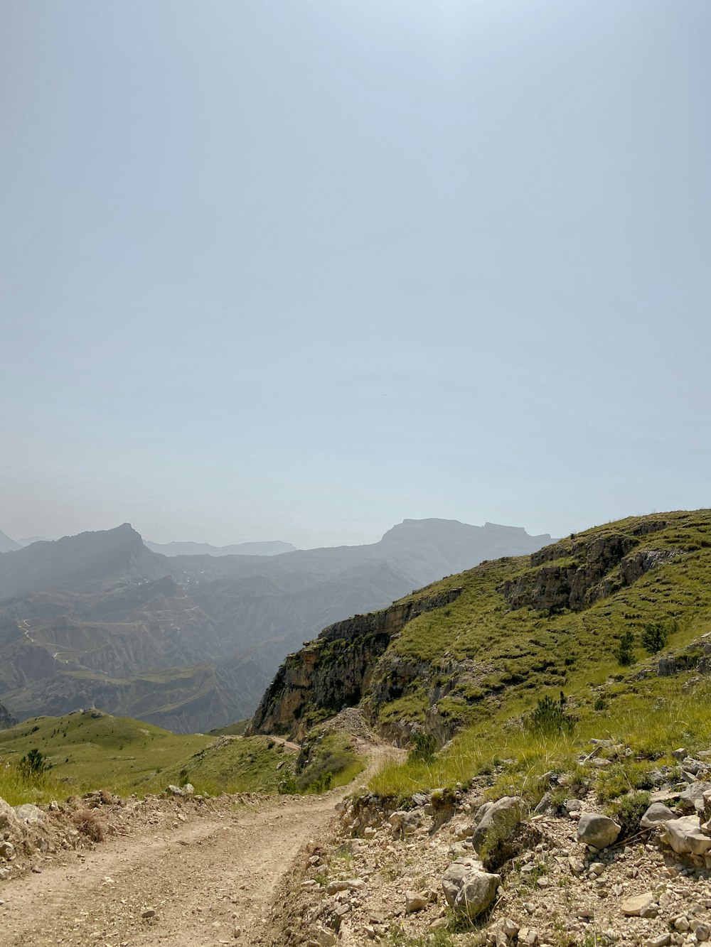 a dirt road going up a hill with mountains in the background