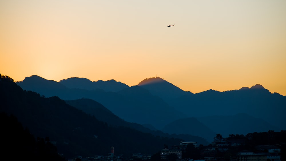 a plane flying in the sky over a mountain range