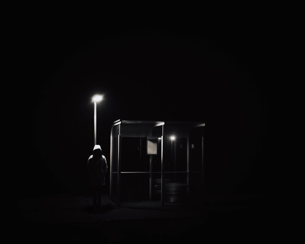 a person standing in the dark next to a light pole