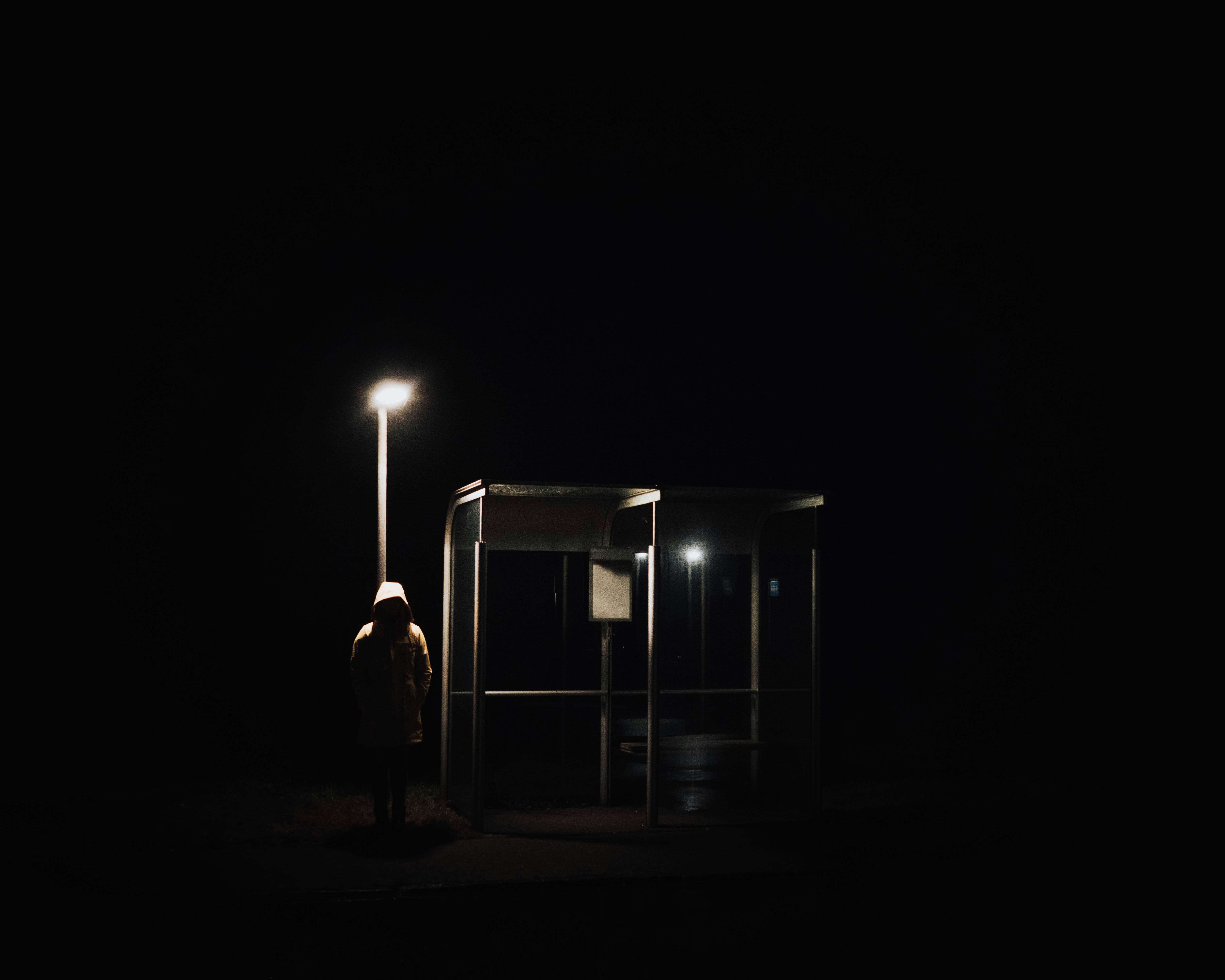 a person standing in the dark next to a bus stop