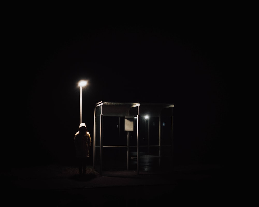 a person standing in the dark next to a bus stop