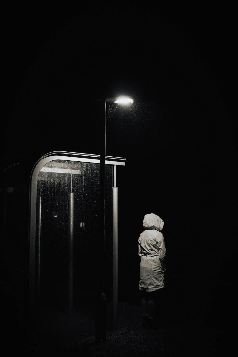 une personne debout sous la pluie la nuit sous un lampadaire