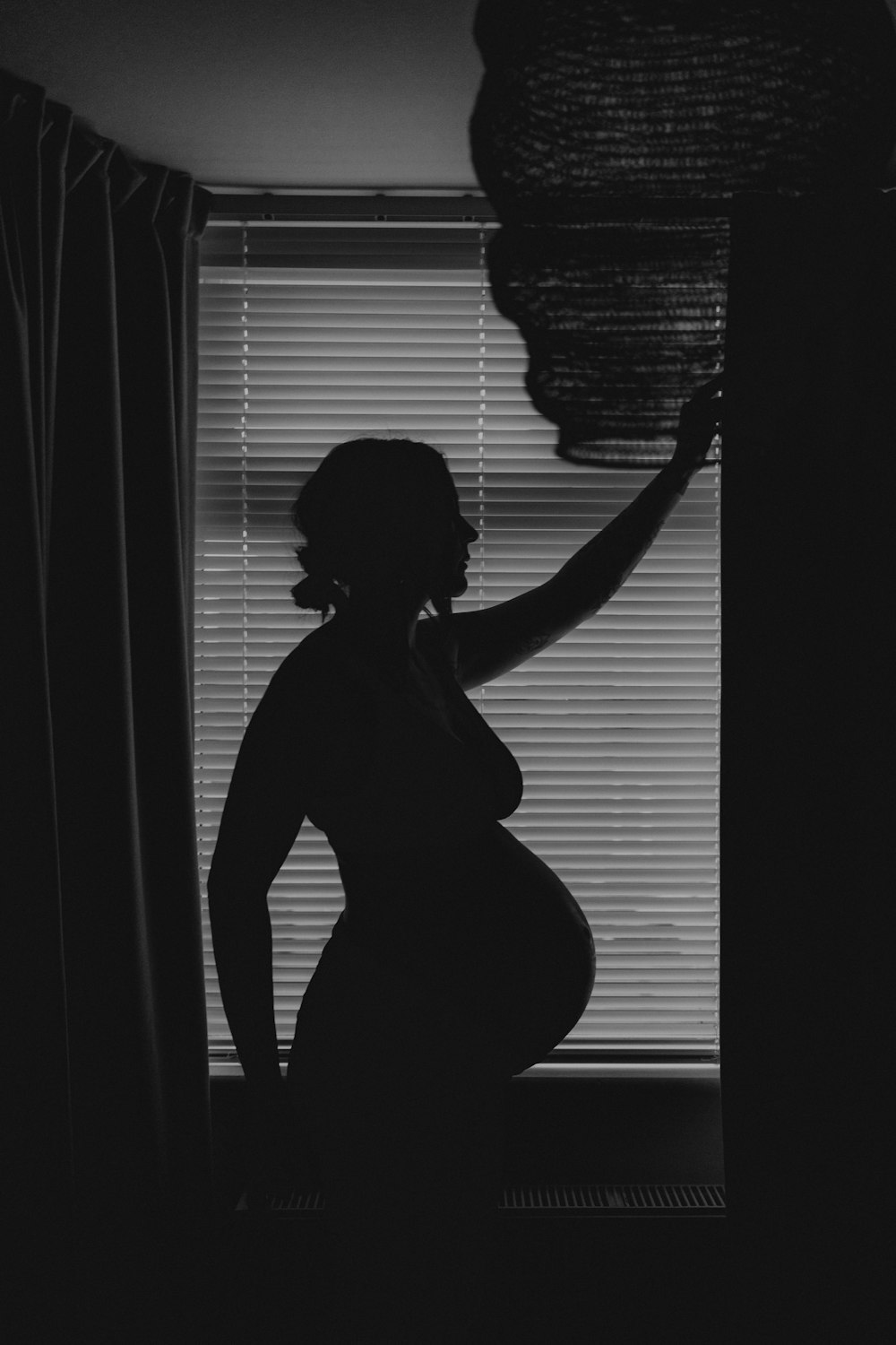uma mulher grávida em pé na frente de uma janela