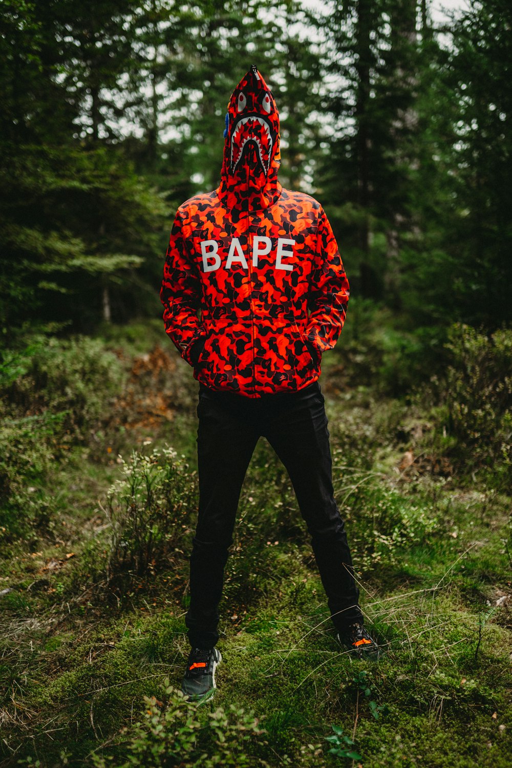 a man in a red leopard print jacket standing in a forest