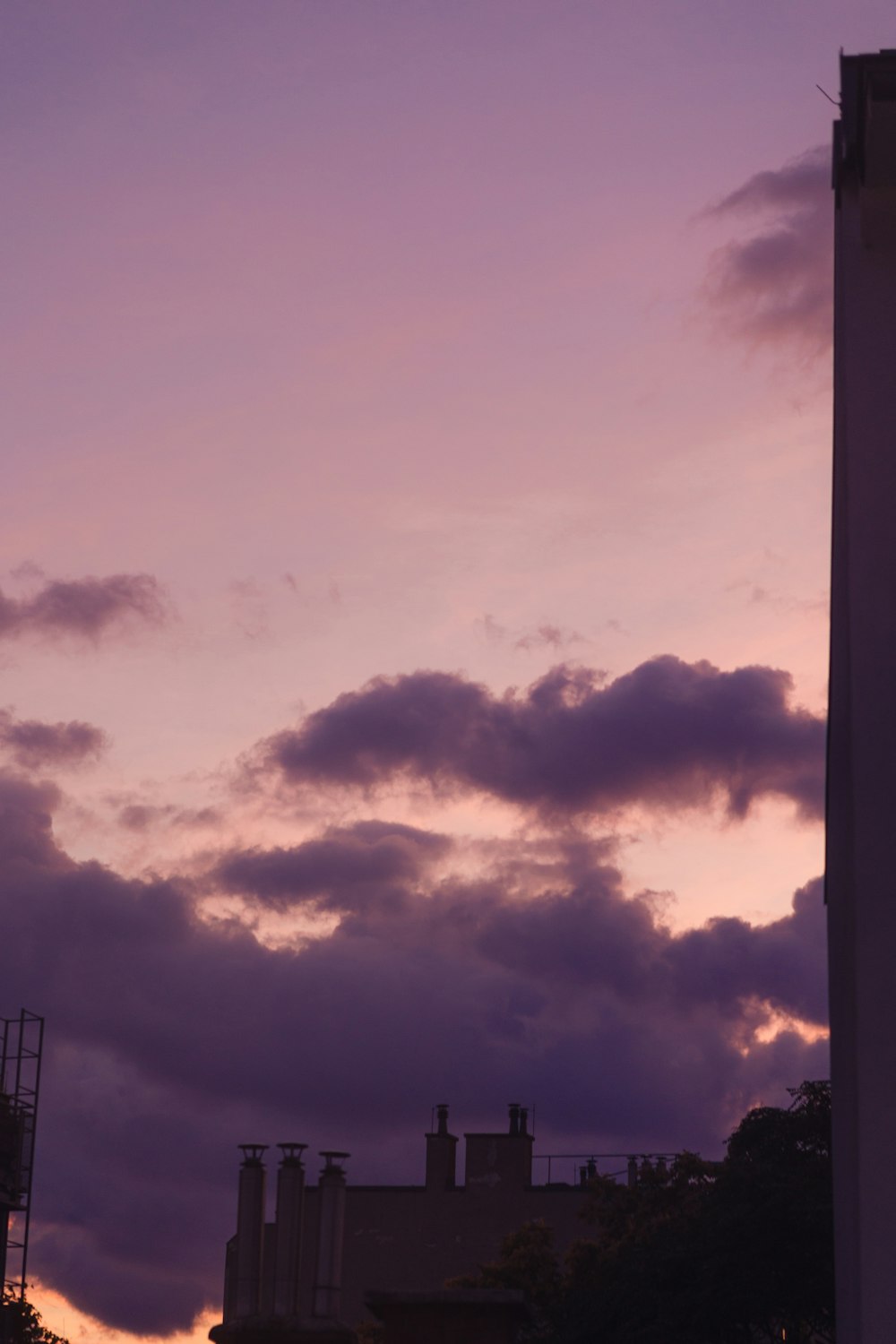 a clock tower is silhouetted against a purple sky