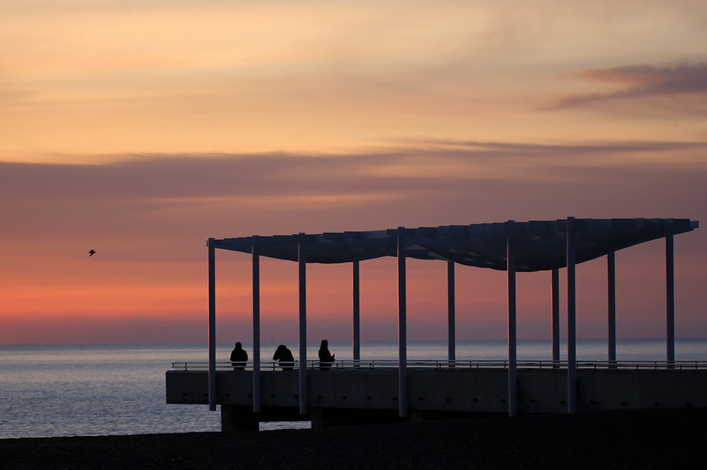 a group of people standing on top of a pier next to the ocean