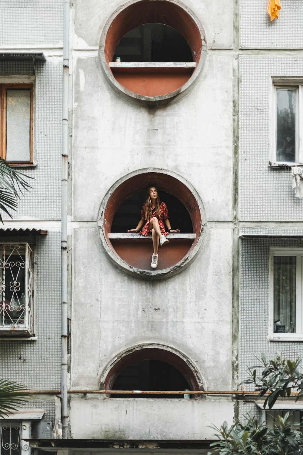 ビルの丸い窓に座る女性