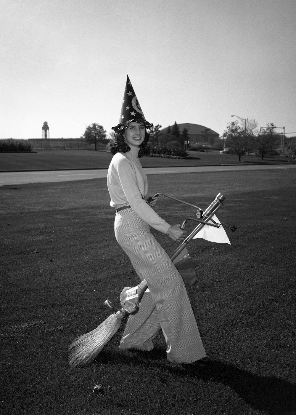 a woman with a hat and a broom in a field