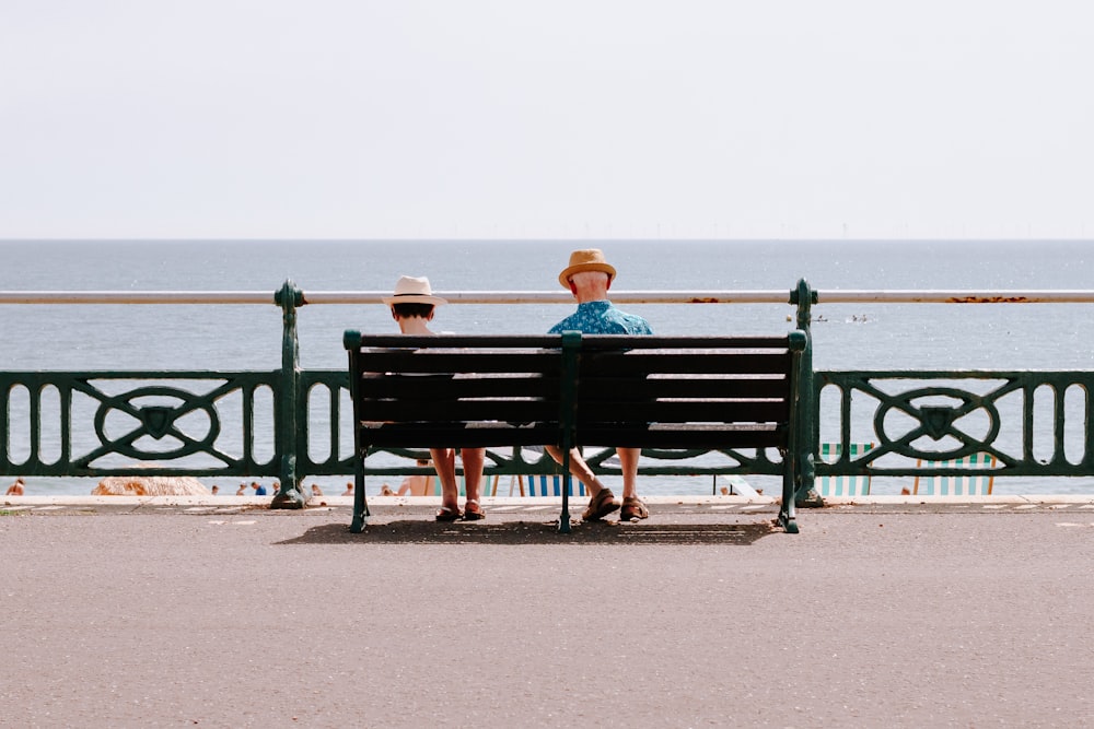 two people sitting on a bench near the ocean