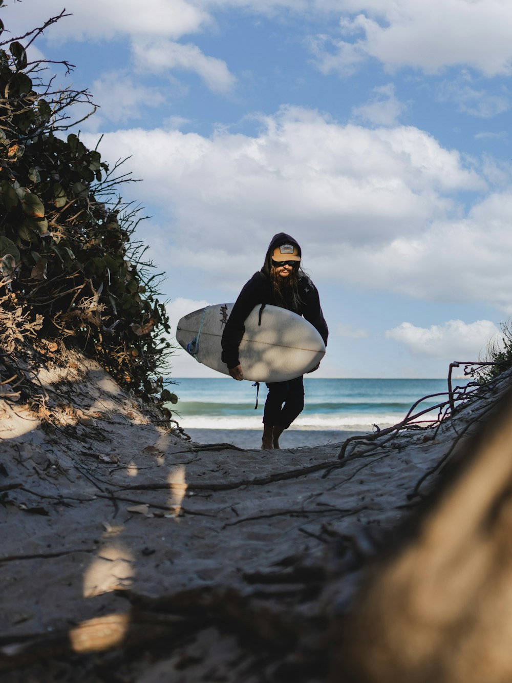 a man carrying a surfboard on top of a sandy beach