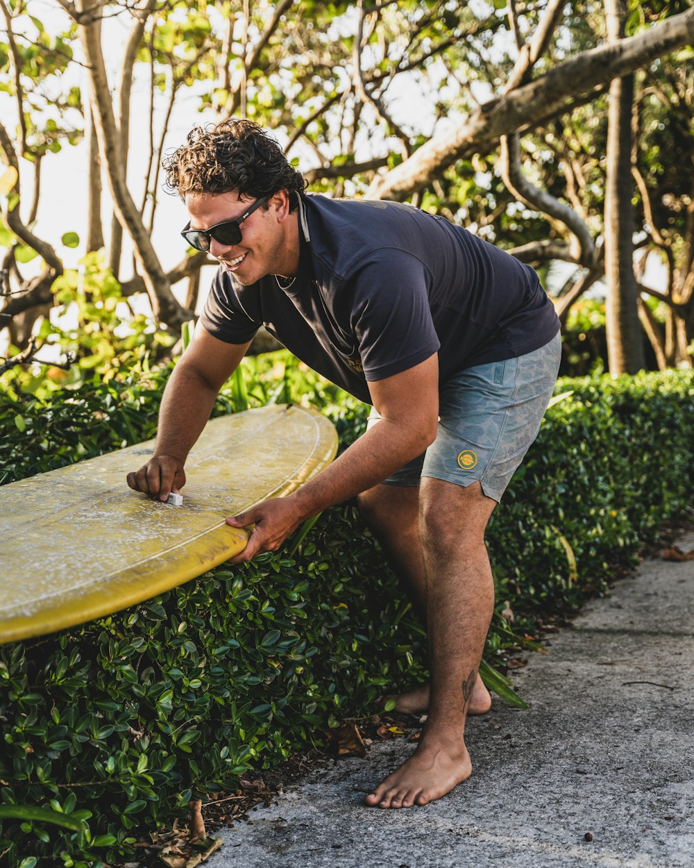 a man holding a yellow surfboard on a sidewalk