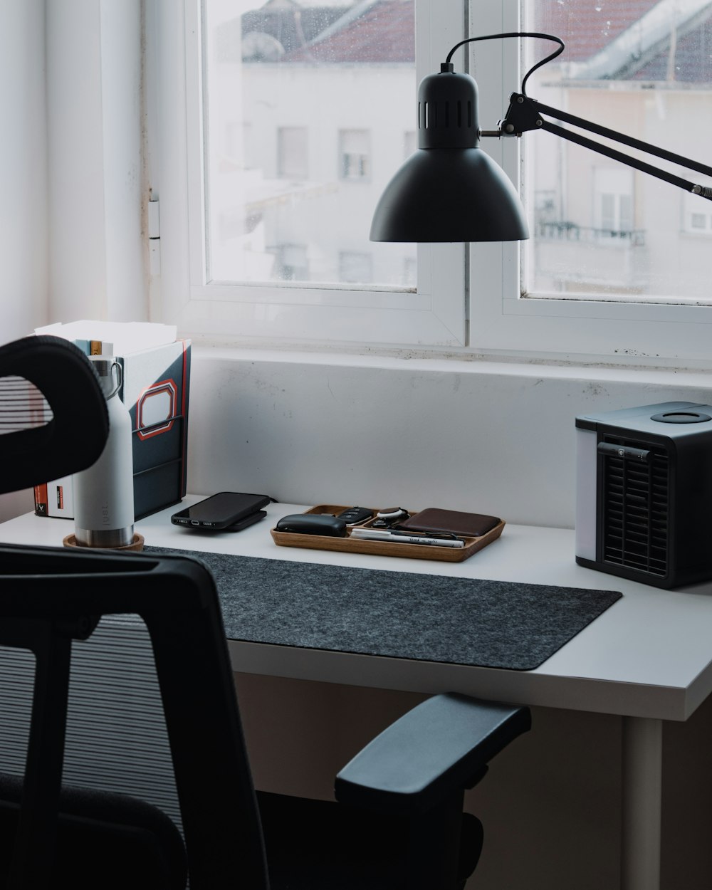 a desk with a computer, a lamp, and a book on it