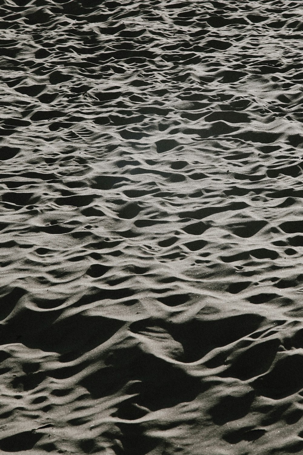 a black and white photo of sand and water