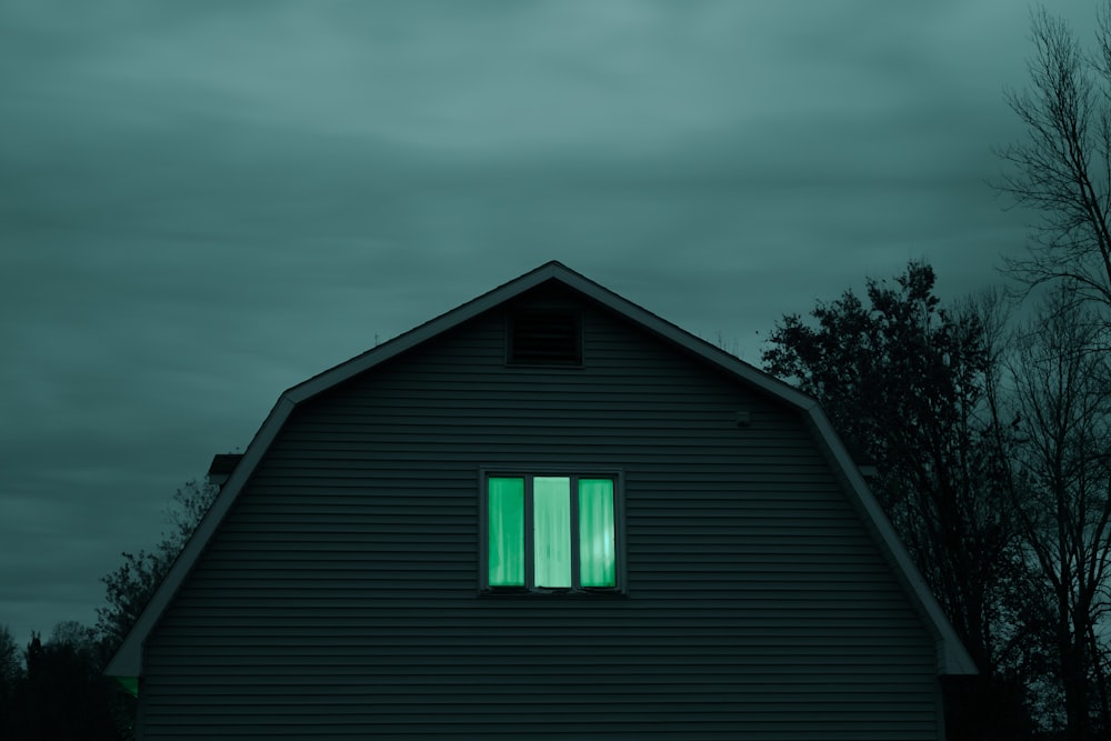 a barn with a green light in the window