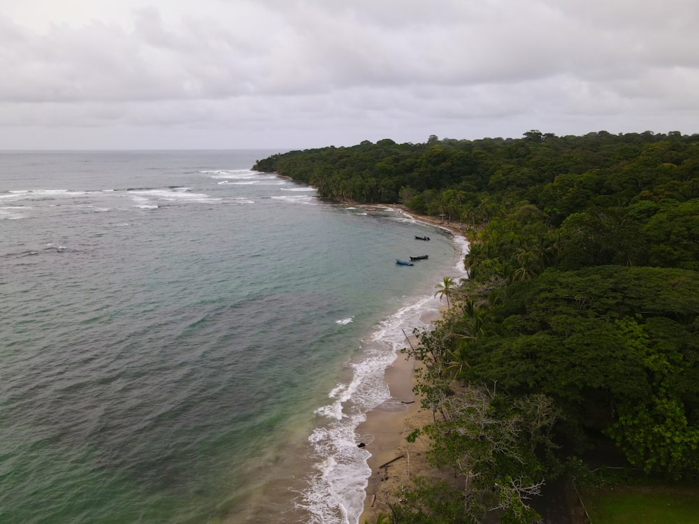 an aerial view of a beach with boats in the water