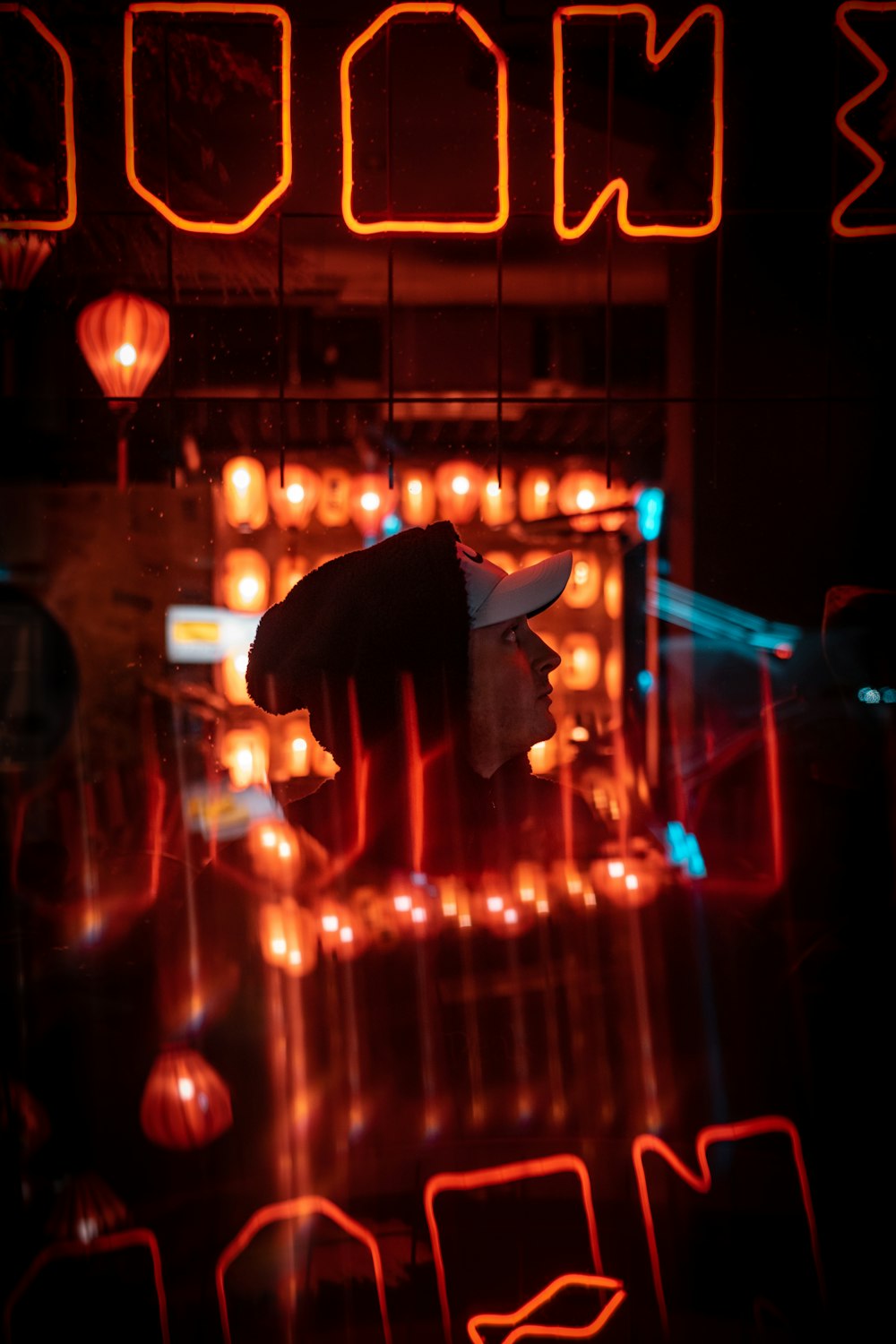 a person wearing a hat standing in front of a neon sign