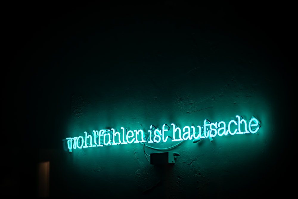 Une enseigne au néon vert sur laquelle on peut lire : Wultuhten ist Hausnace