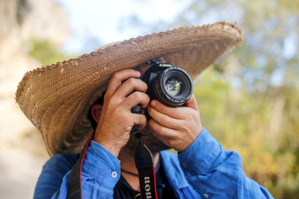 a man wearing a sombrero taking a picture with a camera