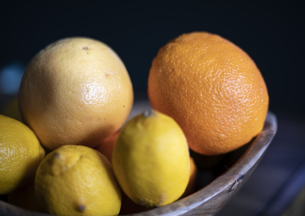 a bowl filled with lemons and oranges on top of a table