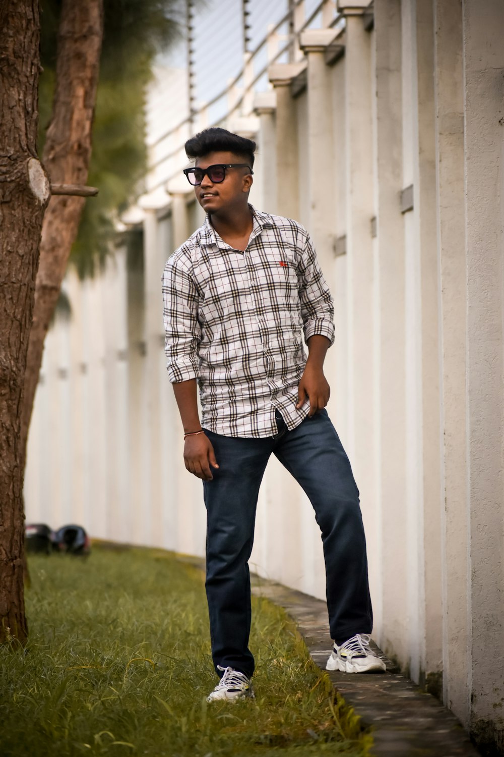 a man standing next to a tree wearing sunglasses