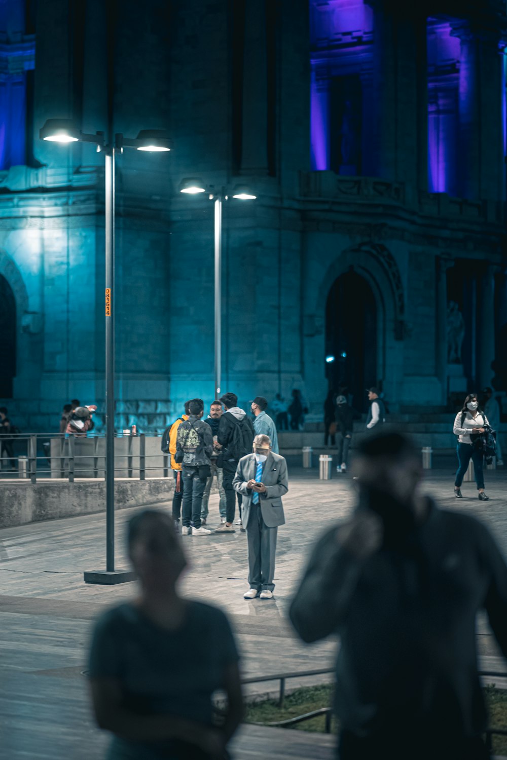 a group of people walking down a street at night