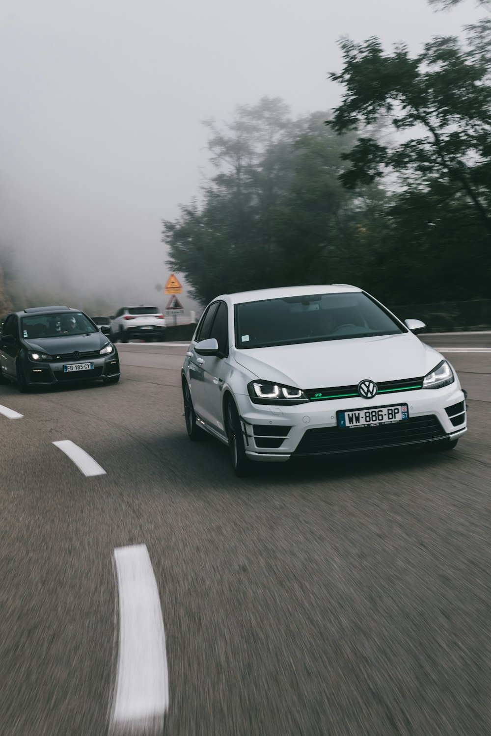 a couple of cars driving down a road