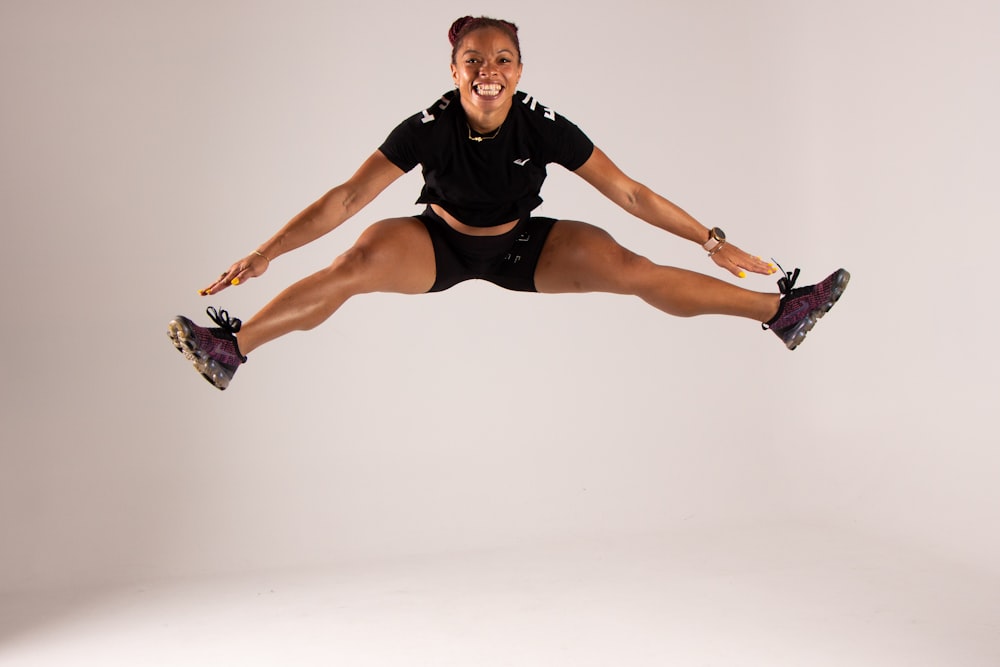 a woman in black shirt and shorts jumping in the air