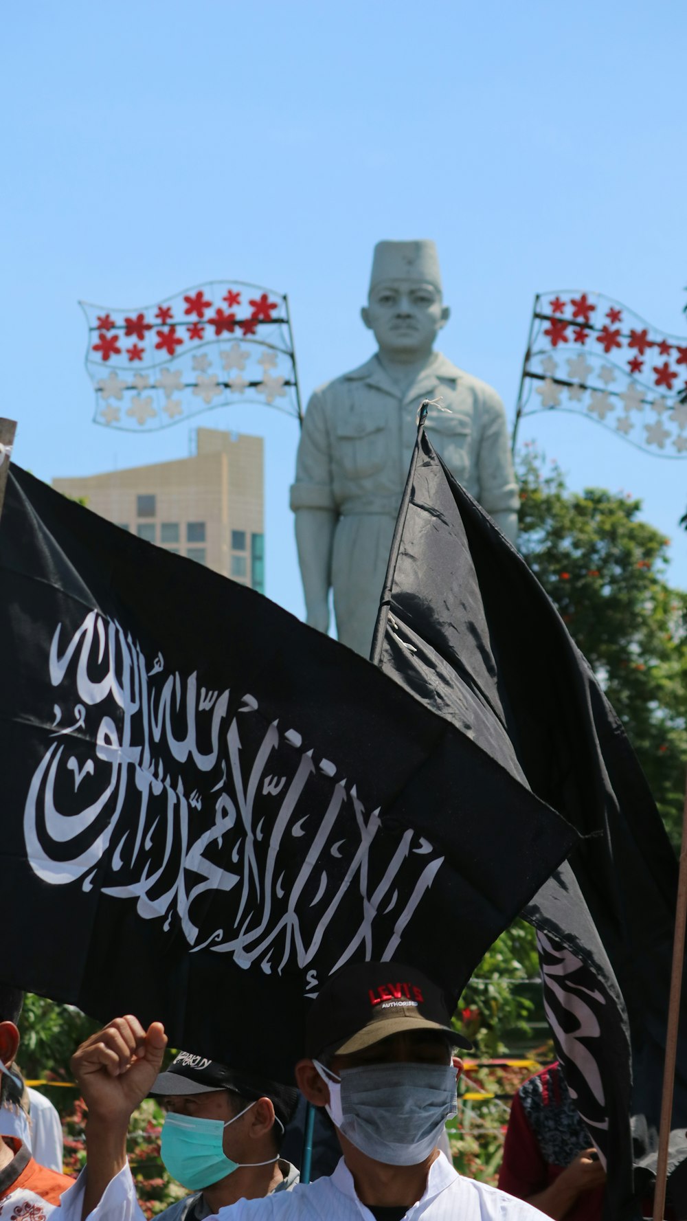 a group of people holding flags in front of a statue