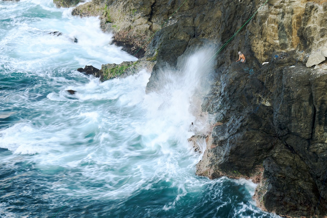 a group of people standing on top of a cliff next to the ocean, Nelayan ditepi jurang. @abyudaily
