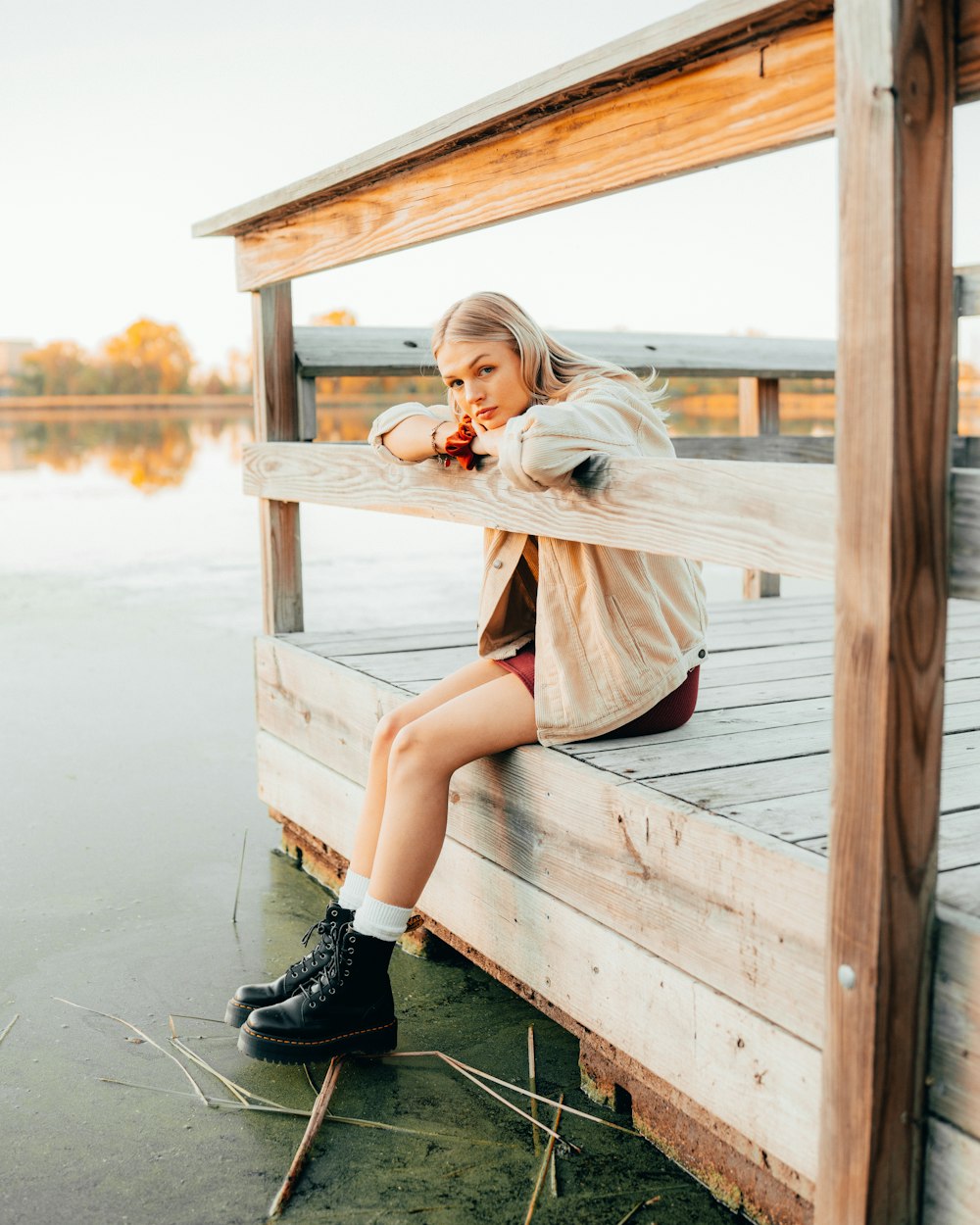 a woman sitting on a wooden dock next to a body of water