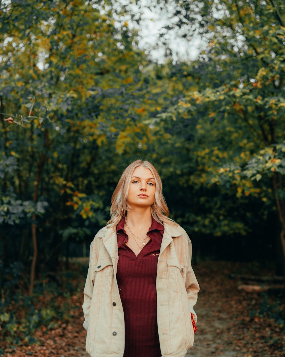 a woman in a red dress is standing in the woods