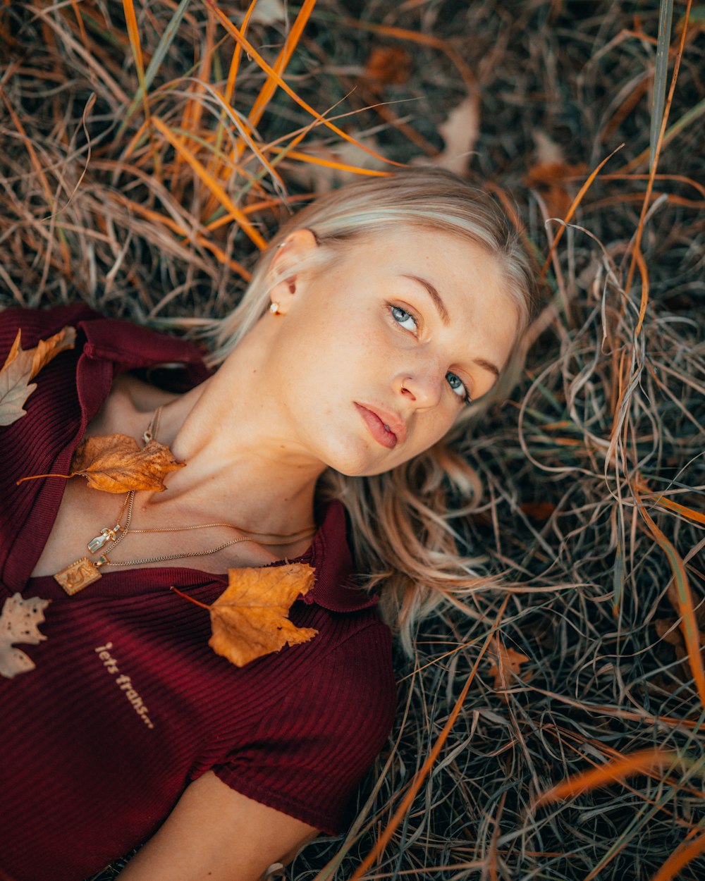 a woman laying in the grass with leaves on her chest