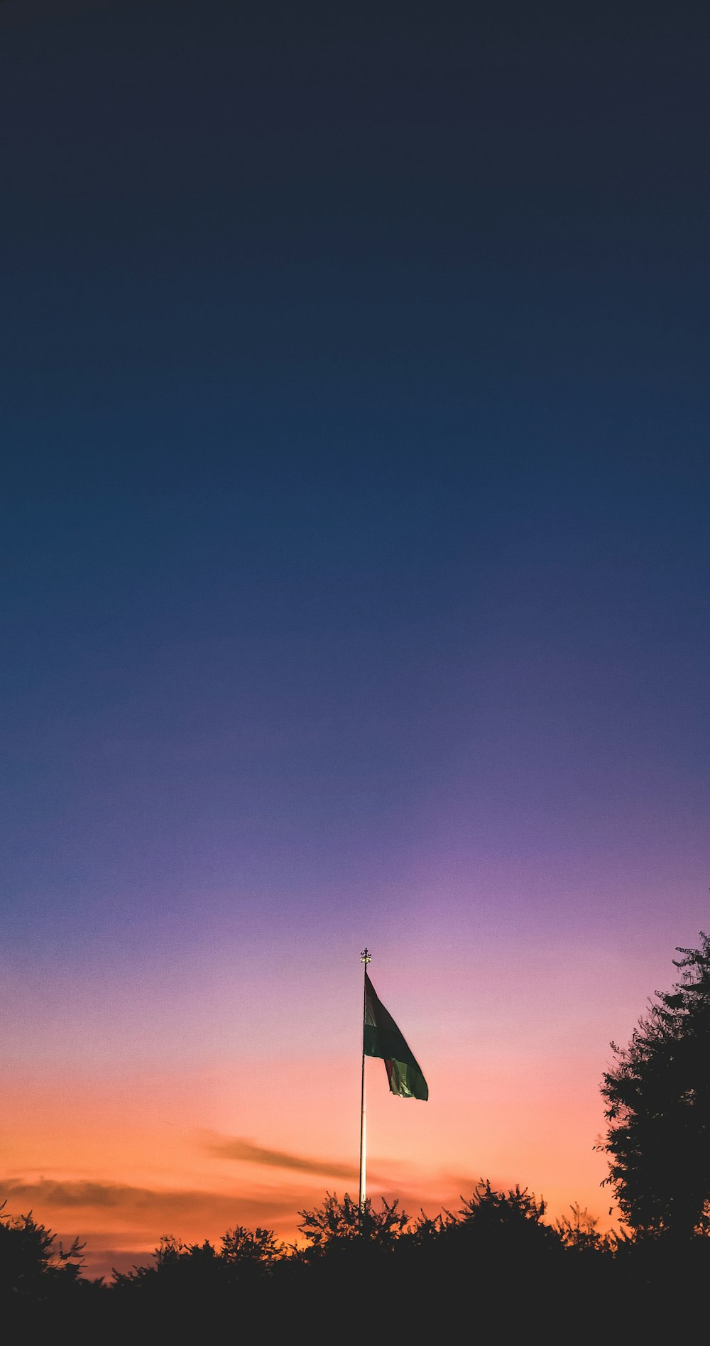 a flag flying in the air at sunset