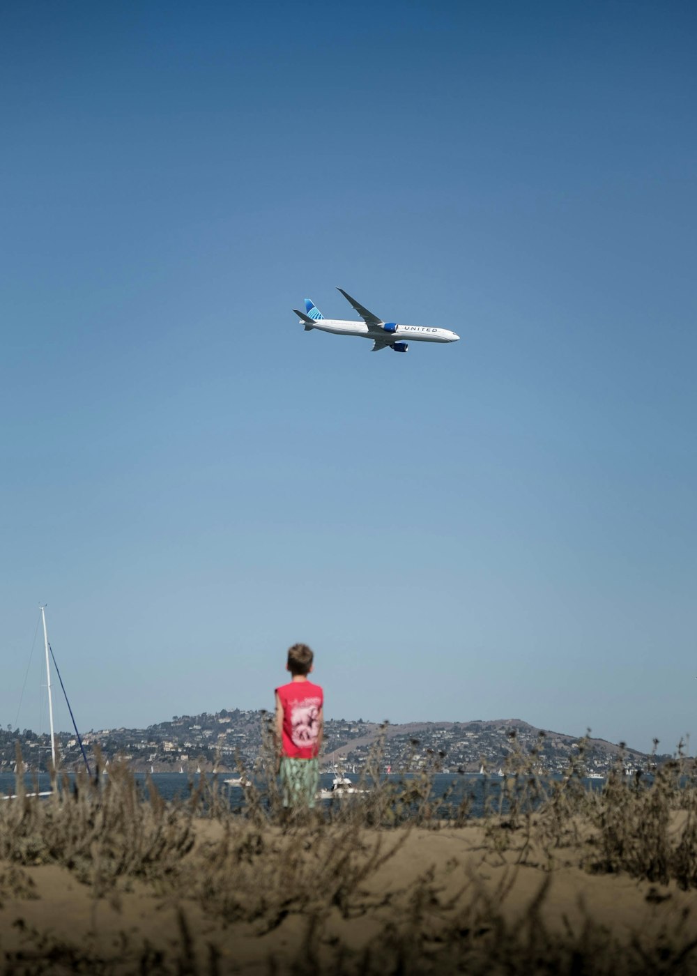 a boy looking at an airplane in the sky