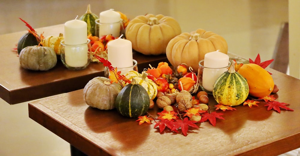 a wooden table topped with candles and pumpkins